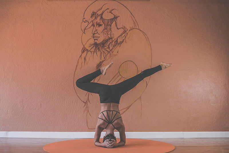 Frau macht Yoga vor Wand mit Kunstwerk.