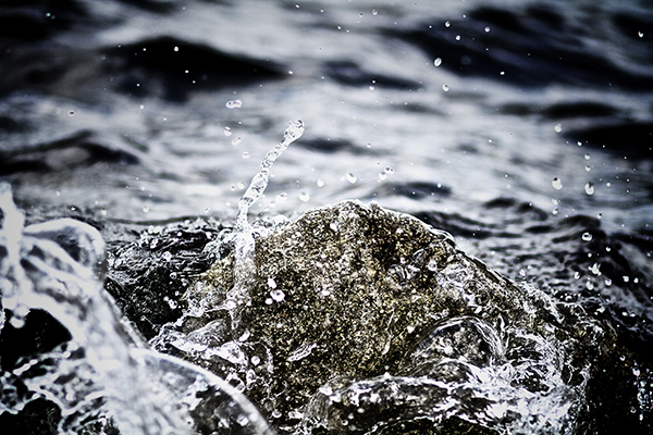 Wasser prallt an Stein auf